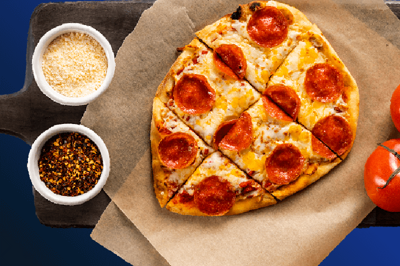 Personal size pepperoni pizza with parmesan and red pepper flakes on the side