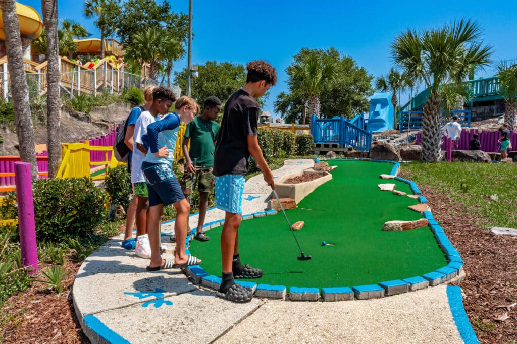 group of teen boys play tropical mini golf